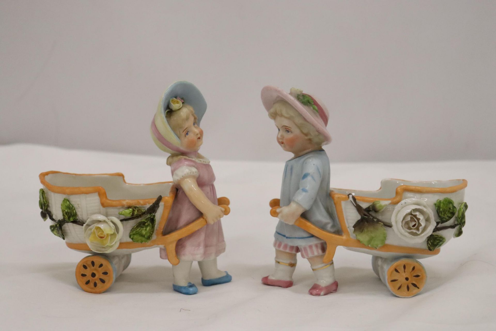 TWO VINTAGE GERMAN FAIRINGS TO INCLUDE TWO GIRLS PULLING FLOWER CARTS, ONE WITH A HAT, THE OTHER - Image 4 of 6