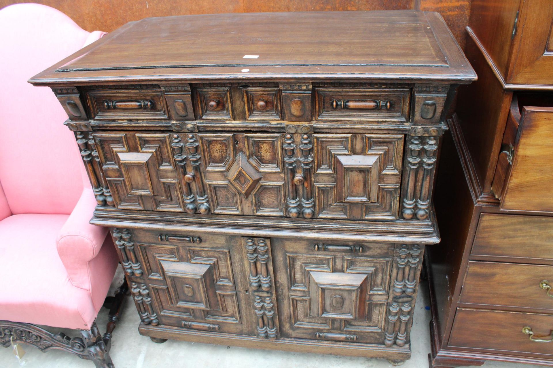 AN OAK CHARLES I STYLE CHEST OF DRAWERS WITH CUPBOARD TO BASE ENCLOSING TWO NINE BOTTLE