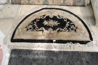 A BLACK PATTERNED HALF MOON FRINGED RUG