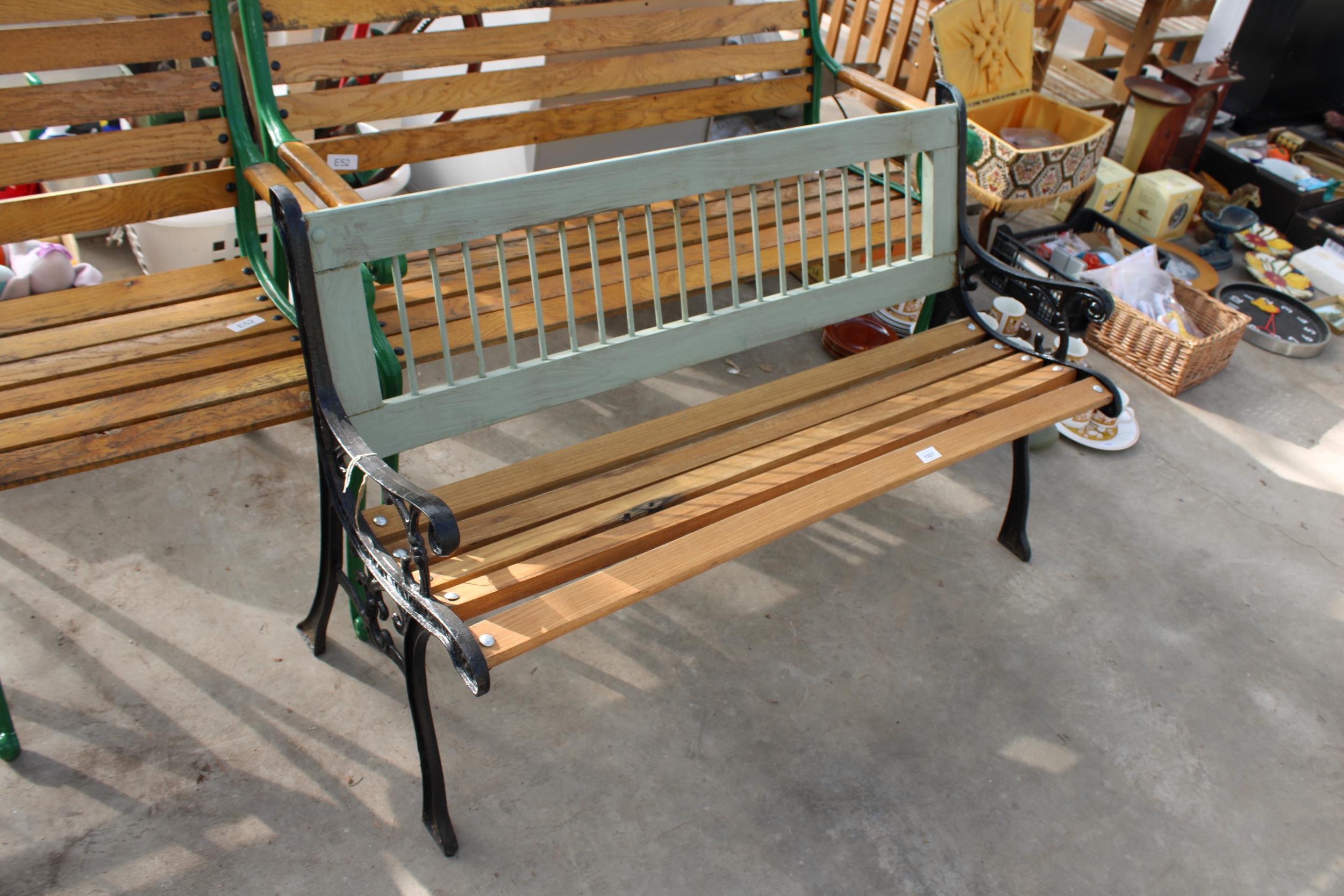 A WOODEN SLATTED GARDEN BENCH WITH DECORATIVE CAST BENCH ENDS