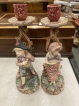 A PAIR OF CERAMIC CANDLE HOLDERS DEPICTING A BOY AND A GIRL