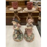 A PAIR OF CERAMIC CANDLE HOLDERS DEPICTING A BOY AND A GIRL