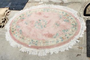 AN OVAL PINK PATTERNED FRINGED RUG