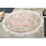 AN OVAL PINK PATTERNED FRINGED RUG