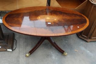 AN OVAL MAHOGANY INLAID AND CROSSBANDED COFFEE TABLE ON PEDESTAL BASE WITH BRASS CLAW FEET AND