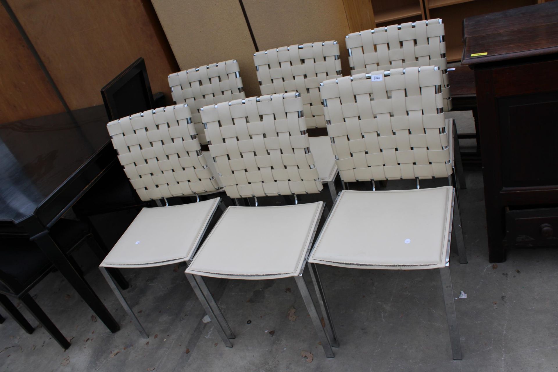 A SET OF SIX POLISHED CHROME DINING CHAIRS WITH CREAM FAUX LEATHER SEATS AND LATTICE BACKS