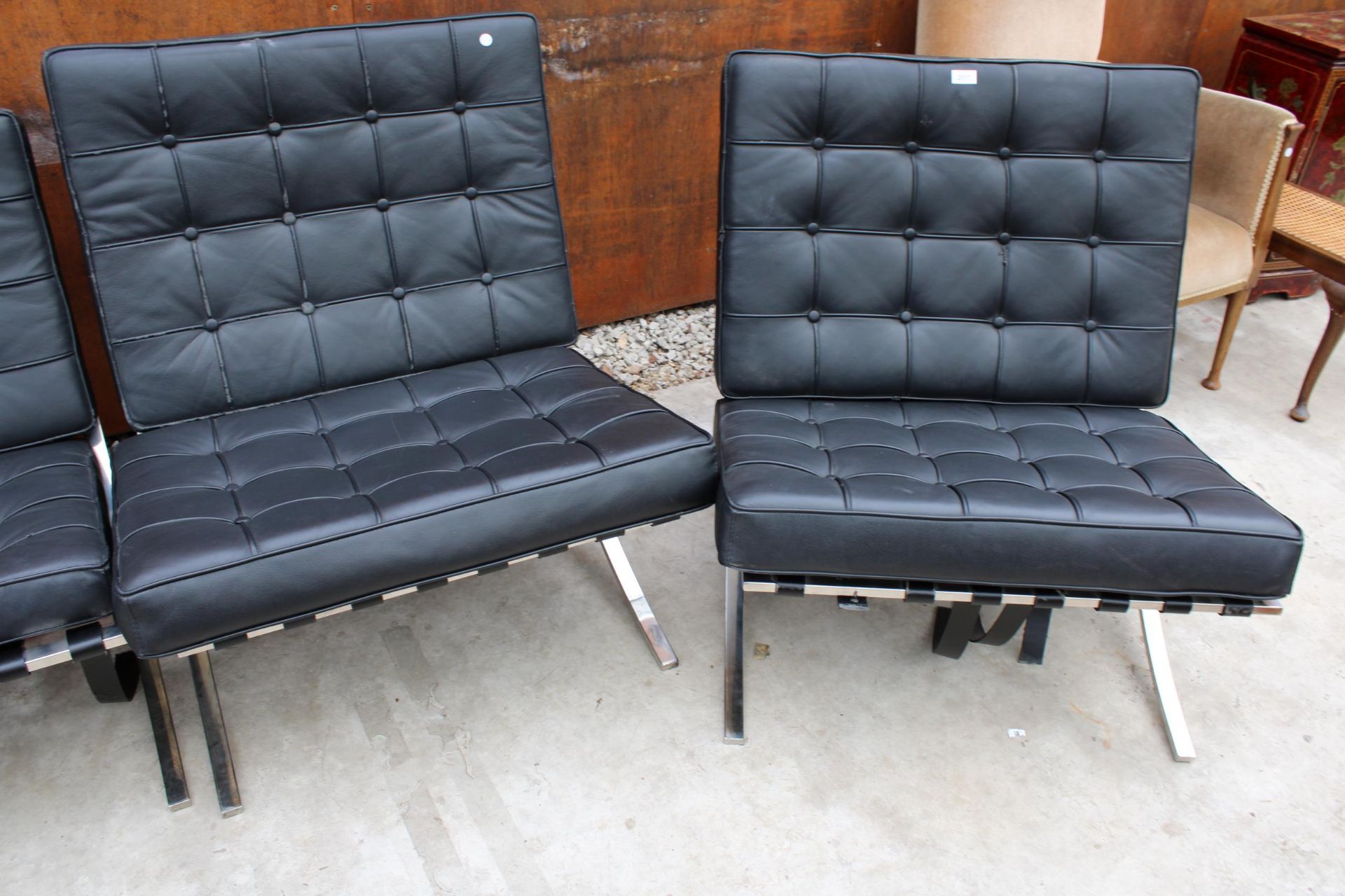 A PAIR OF BLACK BARCELONA STYLE CHAIRS ON POLISHED CHROME X FRAME LEGS
