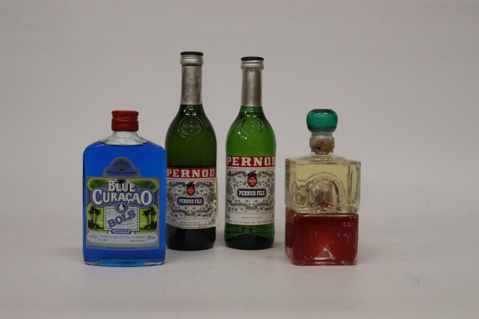 TWO 50CL BOTTLES OF PERNOD FILS, A 37.5CL BOTTLE OF BLUE CURACAO AND A BOTTLE OF