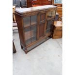 AN EARLY 20TH CENTURY OAK TWO DOOR DISPLAY CABINET ON OPEN BASE WITH TURNED FRONT LEGS, 48" WIDE