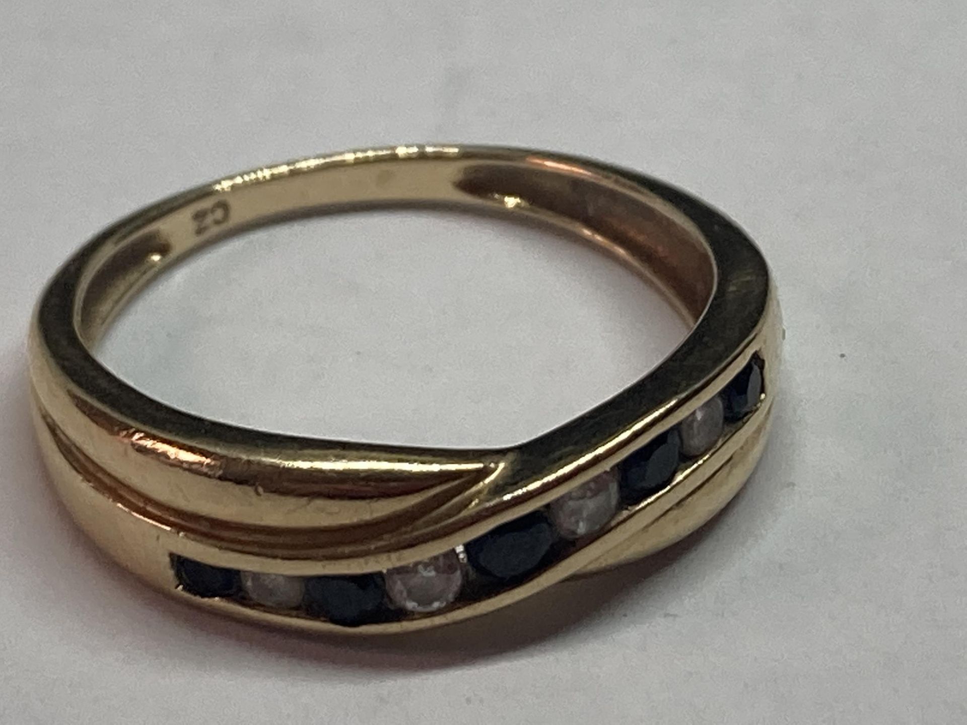 A 9 CARAT GOLD RING WITH IN LINE SAPPHIRES AND CUBIC ZIRCONIAS ON A TWIST SIZE N/O