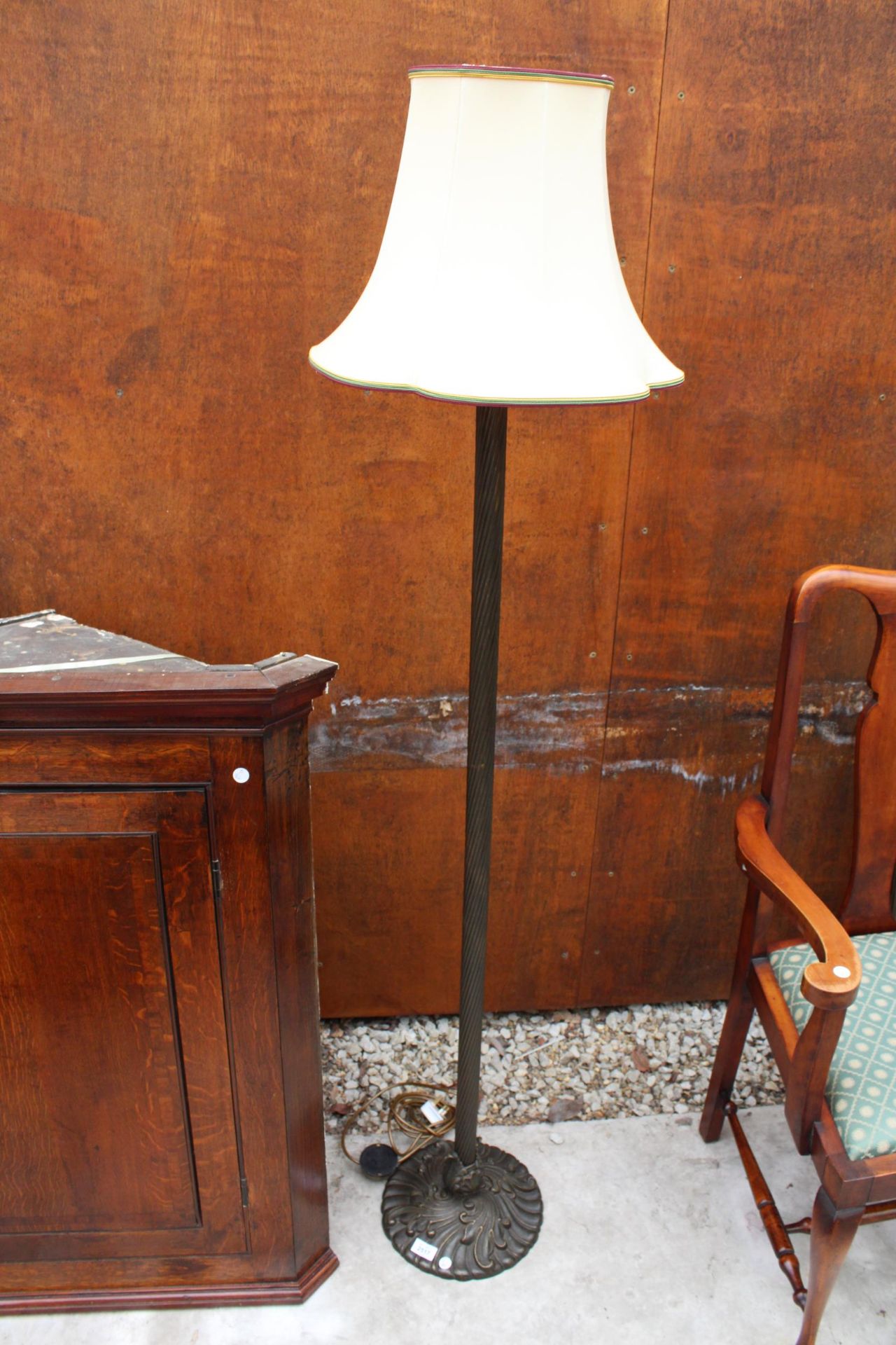 A BRASS STANDARD LAMP ON KNURLED COLUMN AND FOLIATE BASE COMPLETE WITH SHADE