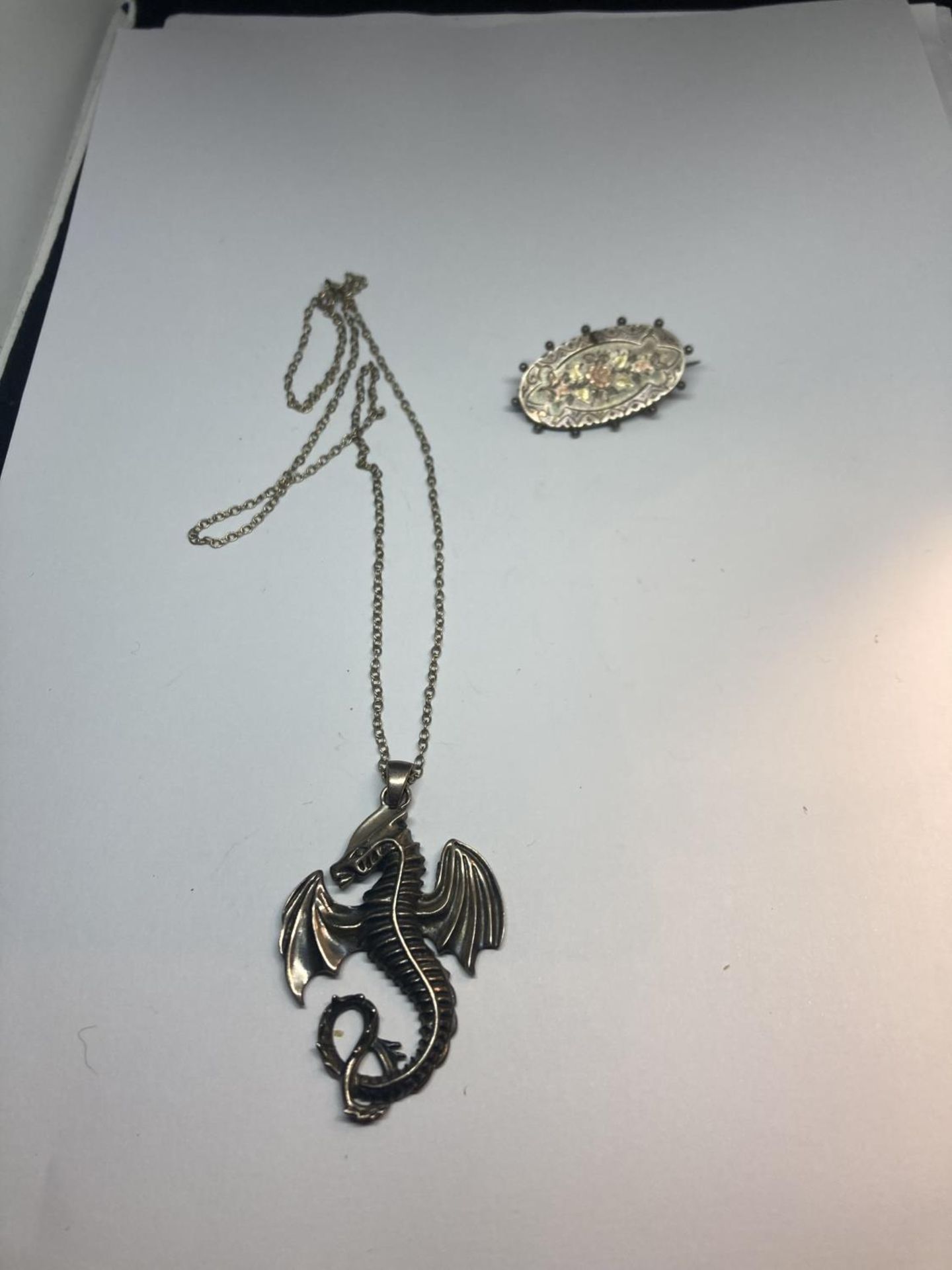 A SILVER NECKLACE WITH AN AMPHIPTERE PENDANT AND A VINTAGE SILVER BROOCH WITH FLORAL DECORATION