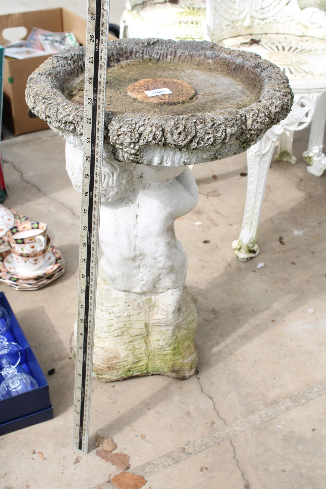 A CONCRETE BIRDBATH WITH CHERUB PEDESTAL BASE