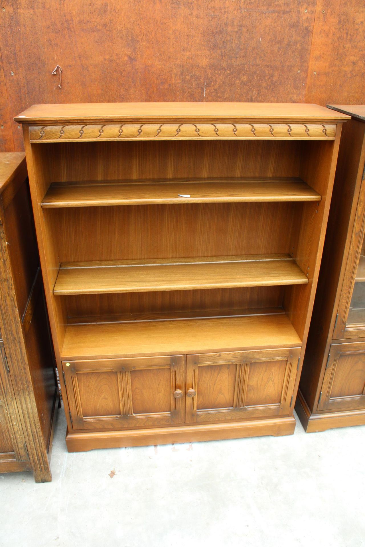 AN ERCOL BLONDE THREE TIER OPEN BOOKCASE WITH CUPBOARD TO BASE, 39.5" WIDE