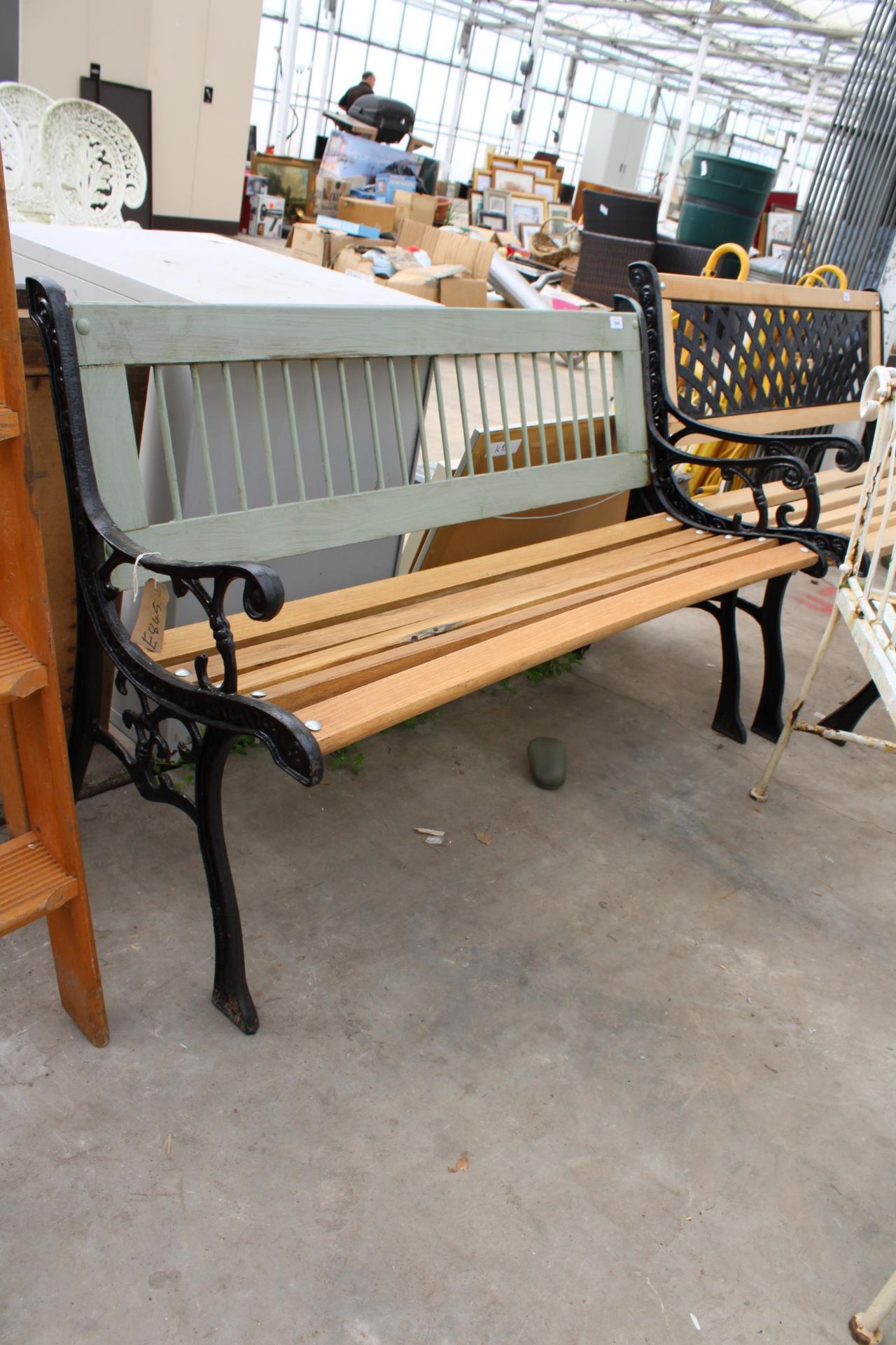 A WOODEN SLATTED GARDEN BENCH WITH DECORATIVE CAST BENCH ENDS