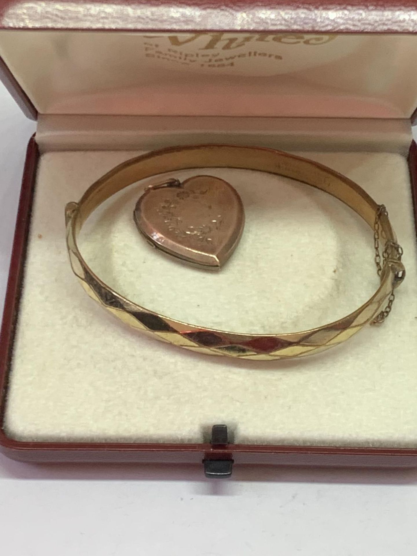 TWO 9 CARAT GOLD PLATED ITEMS - A BANGLE AND A HEART SHAPED LOCKET
