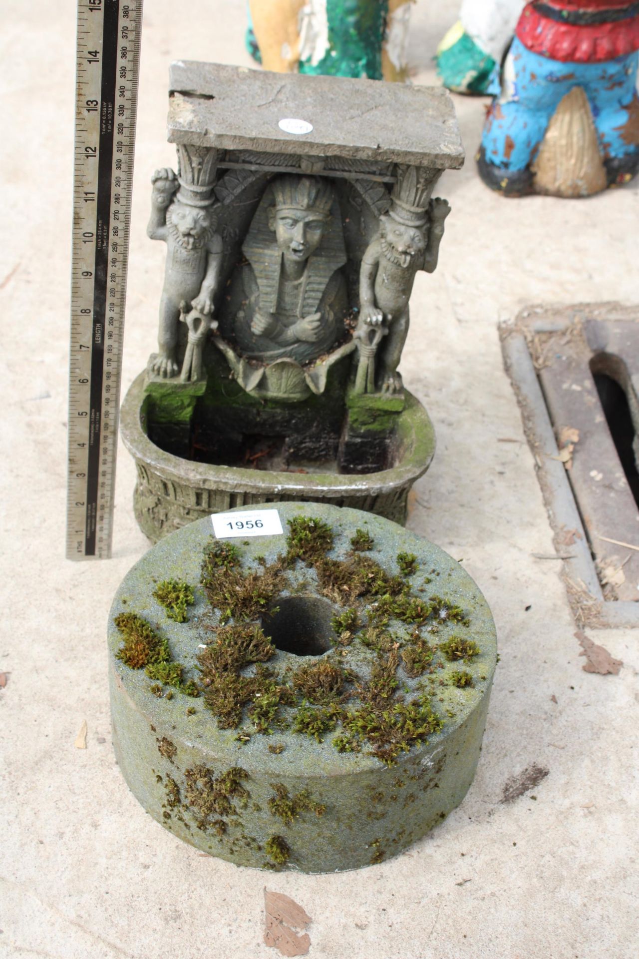 A SMALL GRIND STONE AND A RESIN WALL MOUNTED WATER FEATURE