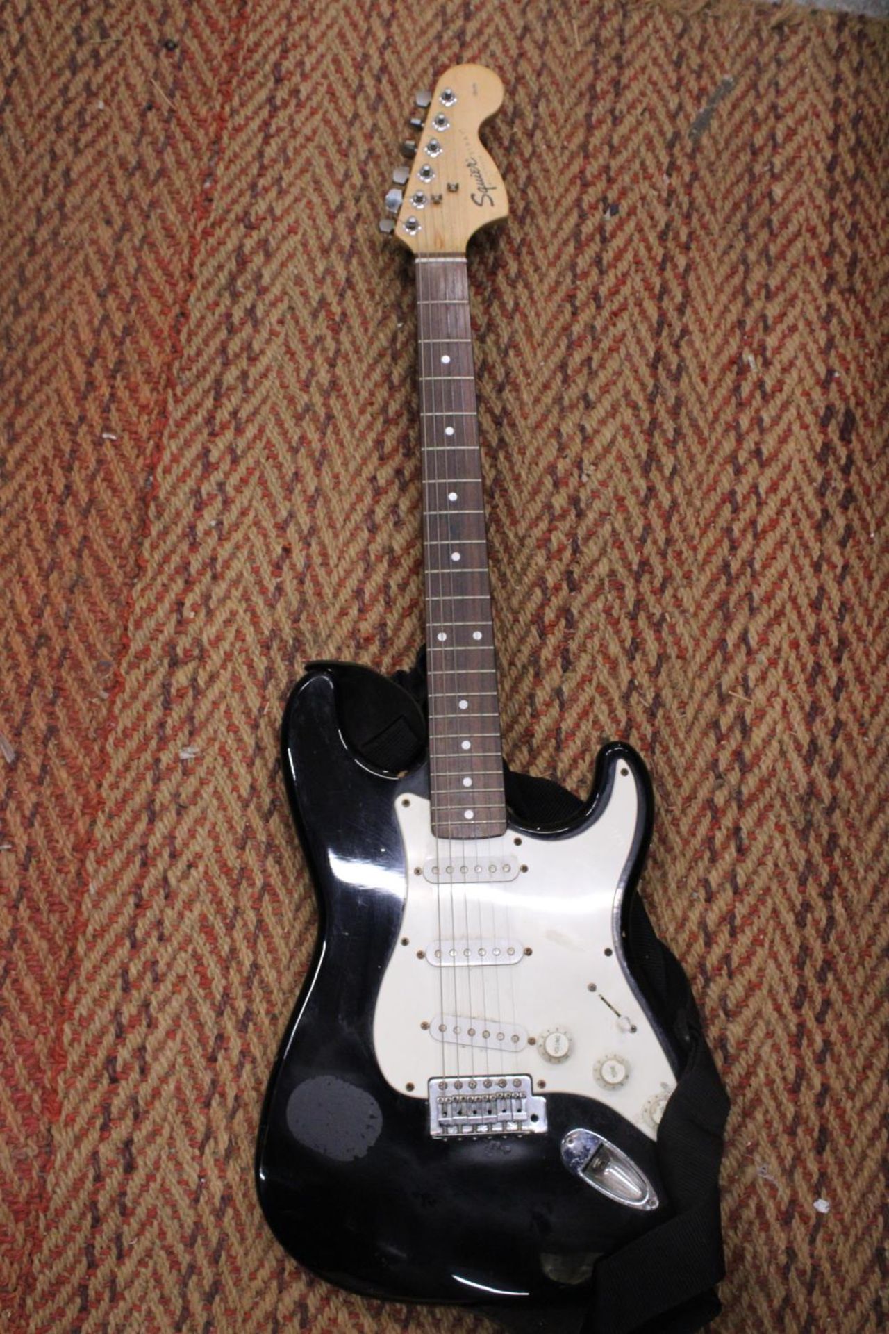 A SQUIER BLACK STRATOCASTER ELECTRIC GUITAR BY FENDER