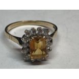 A 9 CARAT GOLD RING WITH A CENTRE CITRINE SURROUNDED BY CUBIC ZIRCONIAS SIZE R