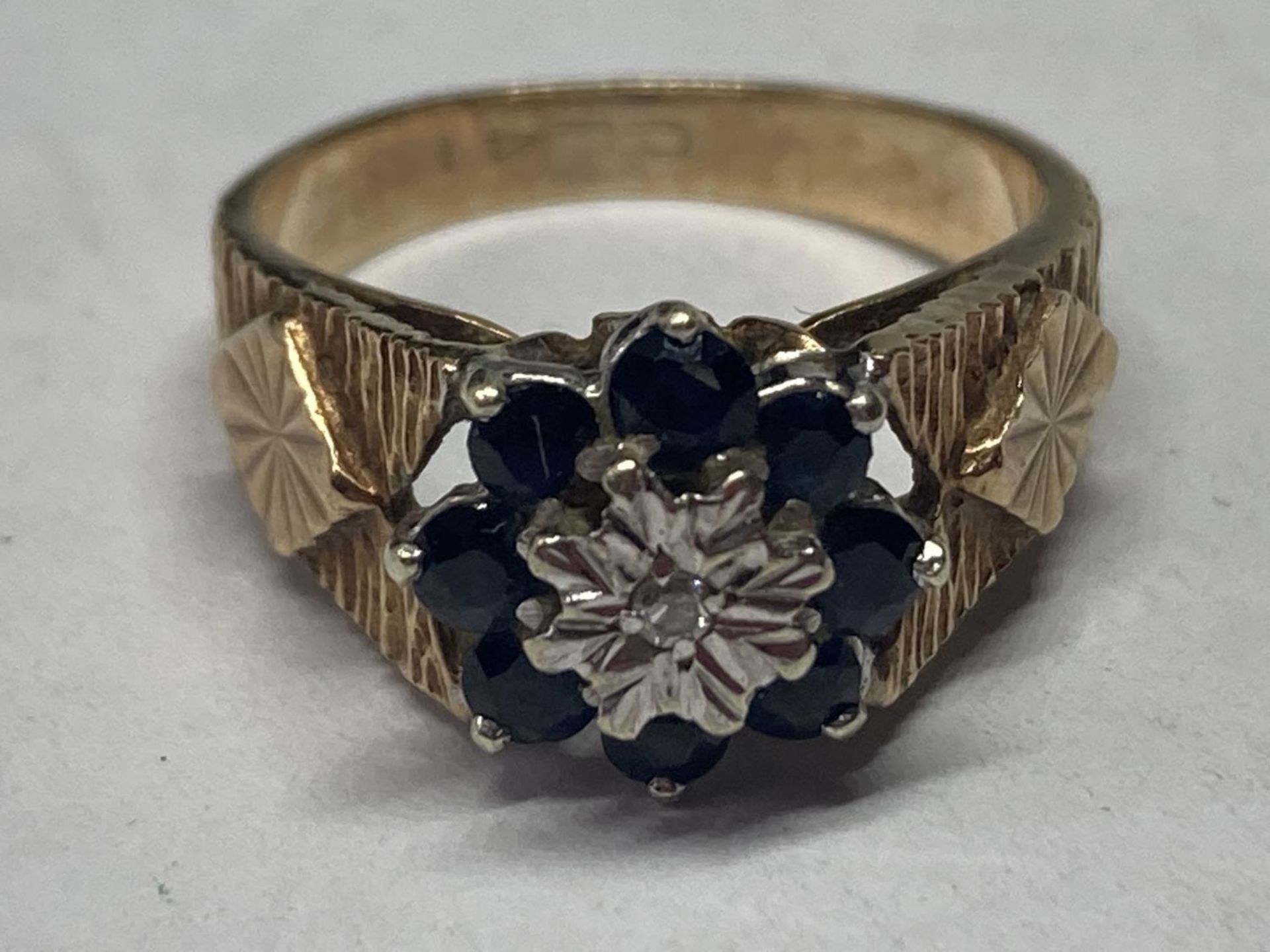 A 9 CARAT GOLD RING WITH CENTRE DIAMOND SURROUNDED BY SAPPHIRES SIZE J
