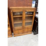 AN ERCOL BLONDE TWO DOOR BOOKCASE WITH CUPBOARDS TO BASE 39.5" WIDE