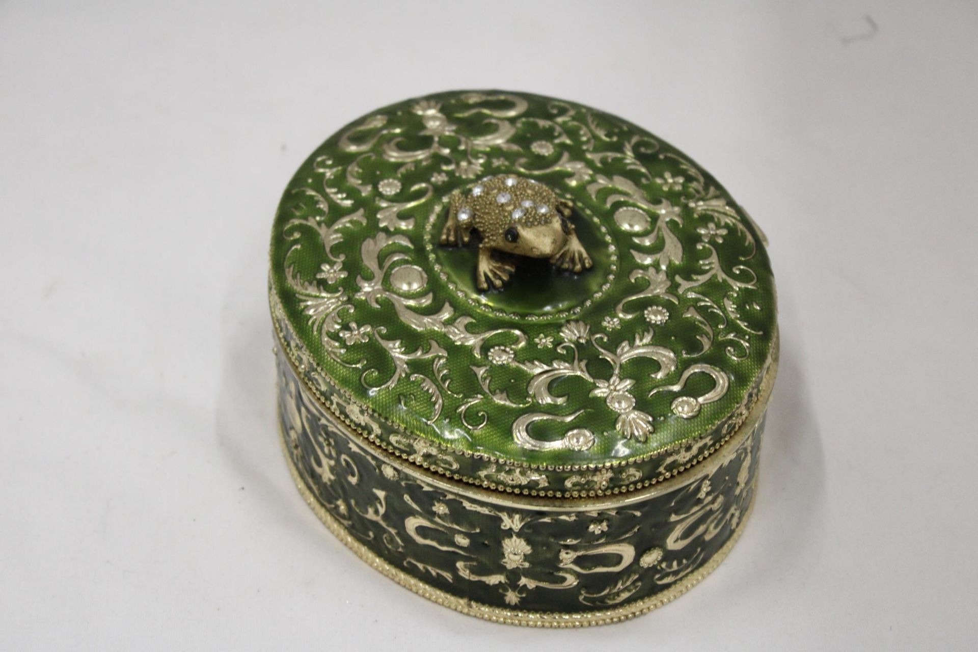 A GREEN ENAMELLED KEEPSAKE/JEWELLERY BOX WITH A JEWELLED FRONG ON THE LID, HEIGHT 8CM, DIAMETER,