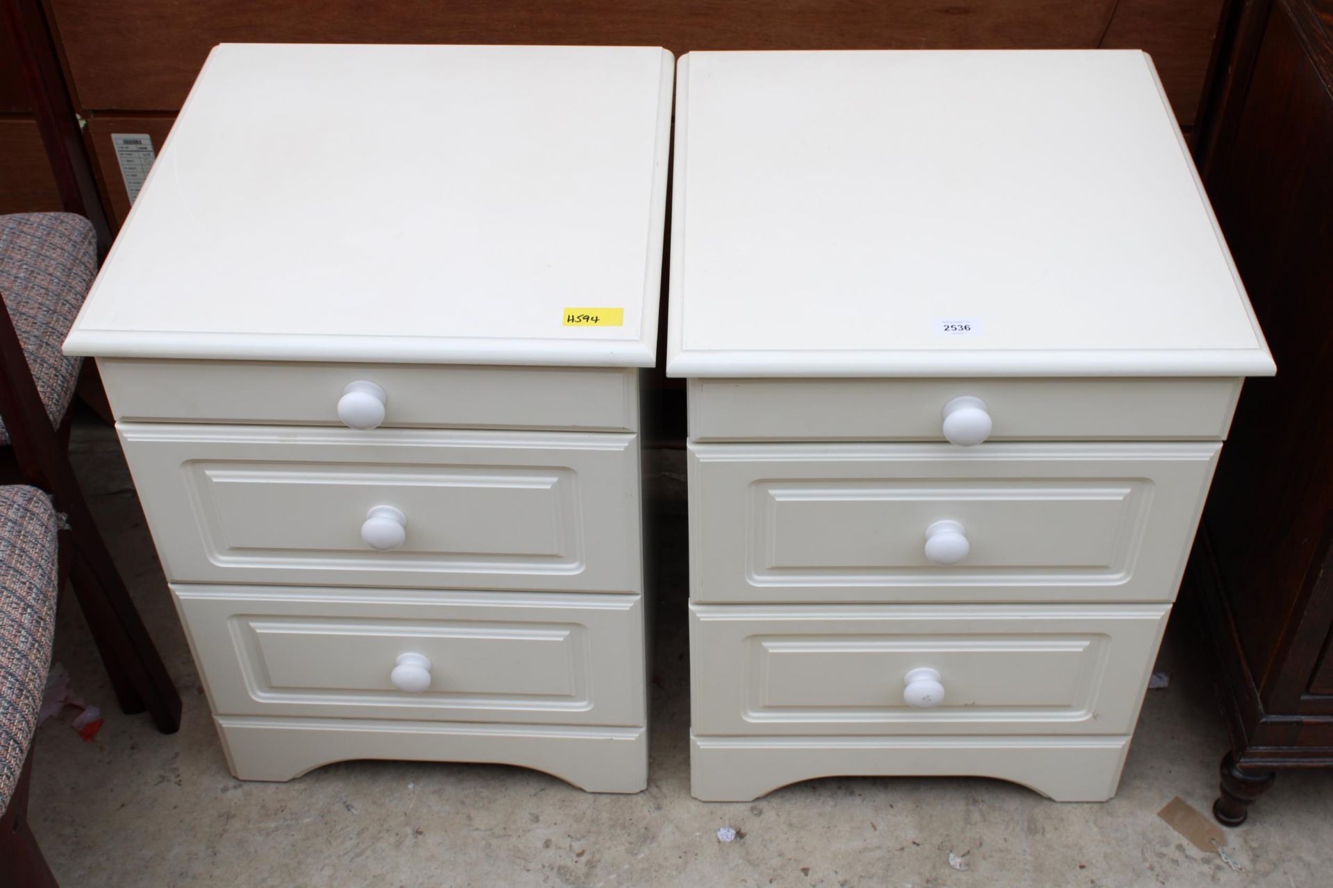 A PAIR OF CREAM BEDSIDE CHESTS OF THREE DRAWERS