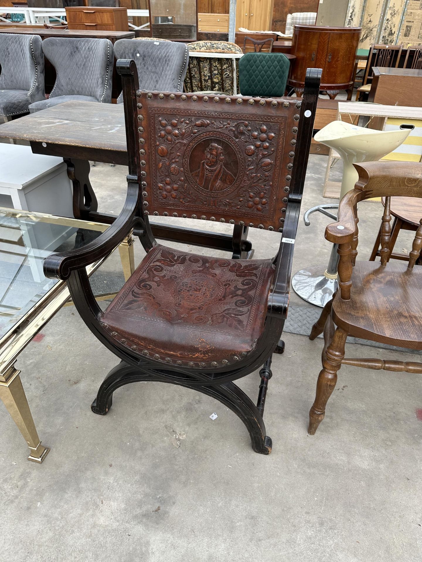 A VICTORIAN CROSS FRAMED ELBOW CHAIR WITH EMBOSSED LEATHER BACK AND SEAT