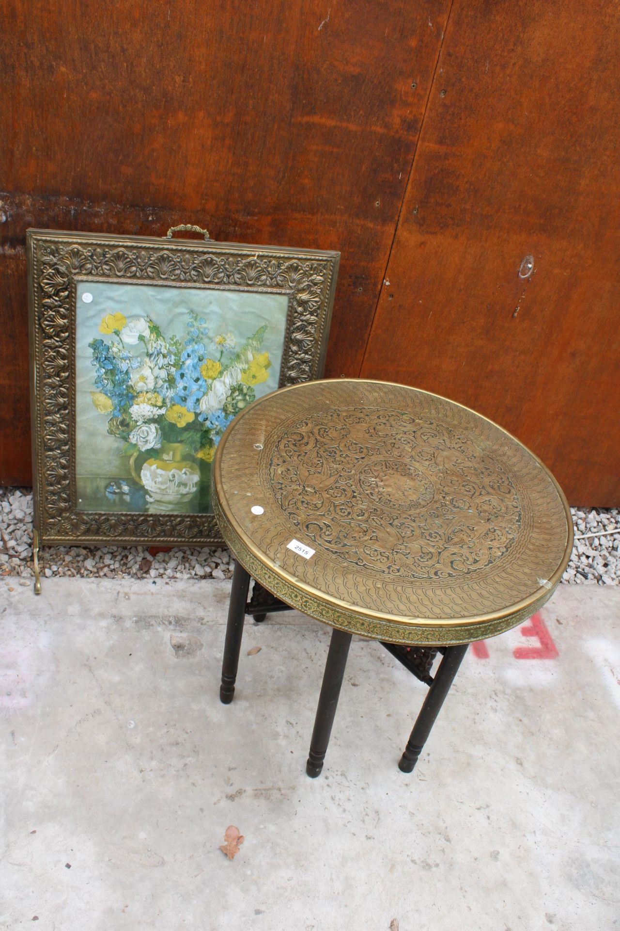 AN INDIAN STYLE BRASS TOP 23.5" SIDE TABLE ON FOLDING BASE WITH EMBOSSED BRASS FIRE GUARD