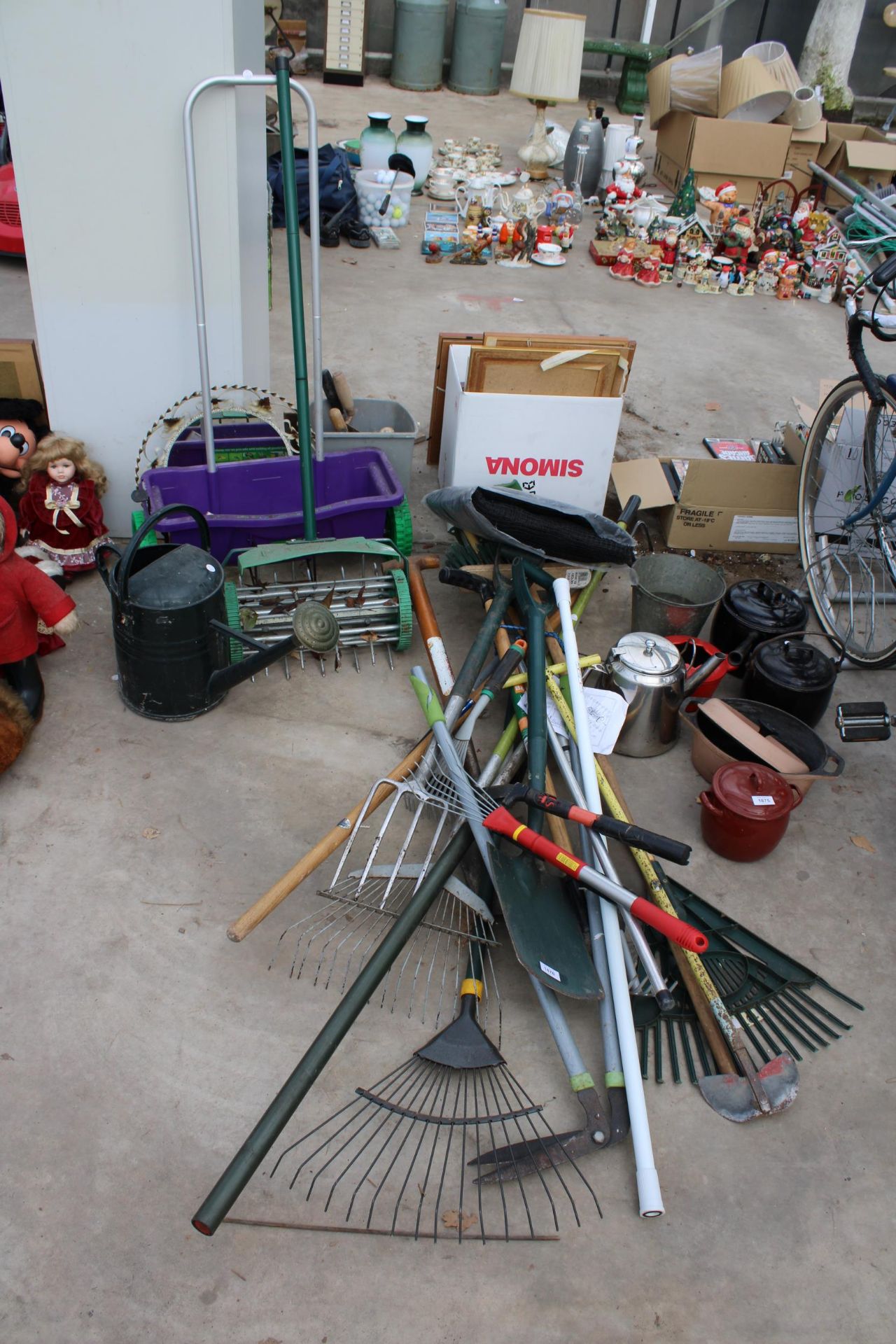 AN ASSORTMENT OF GARDEN ITEMS TO INCLUDE SPADES, FORKS, RAKES AND A SEEDER ETC