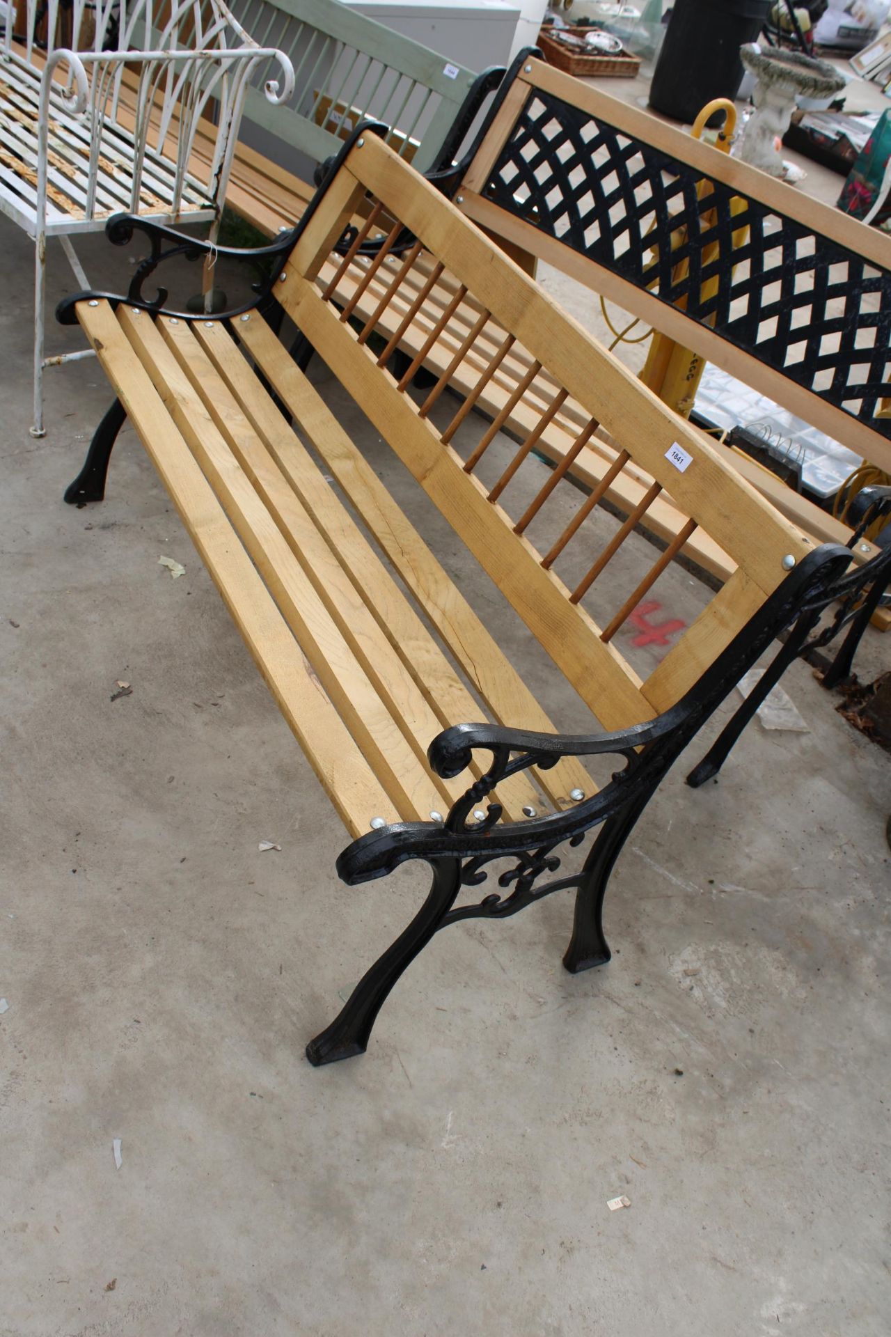 A WOODEN SLATTED GARDEN BENCH WITH CAST BENCH ENDS