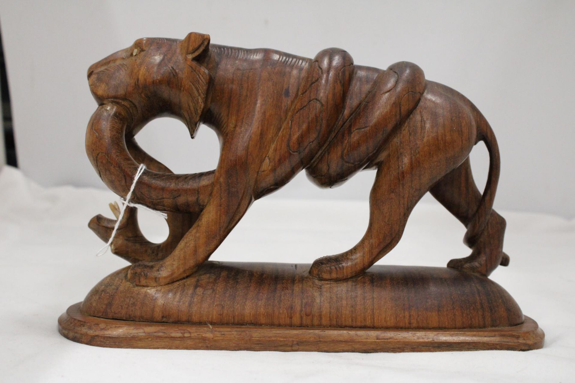 A CARVED WOODEN BIG CAT WITH A SNAKE, HEIGHT 17CM, LENGTH 28CM