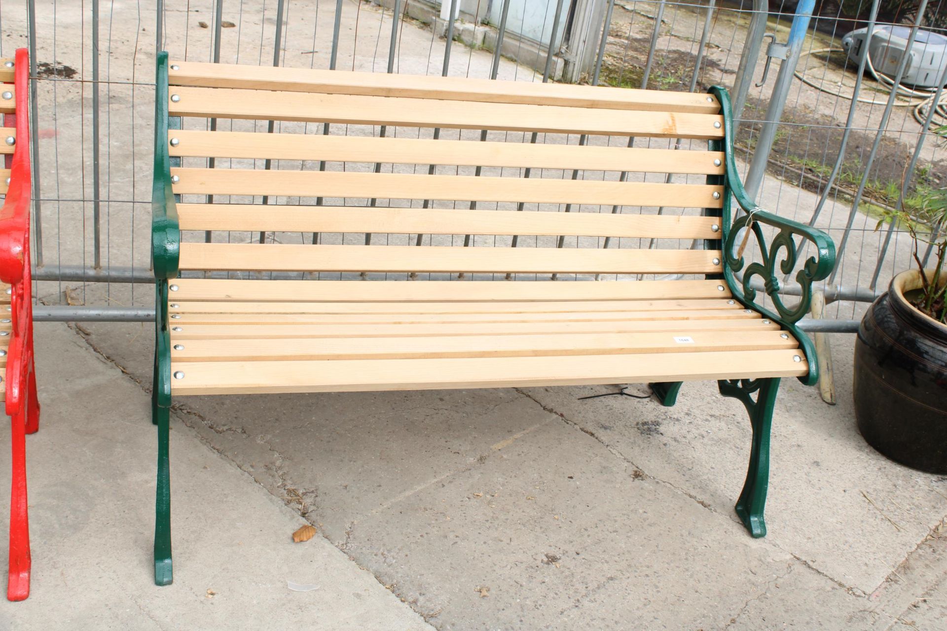 A WOODEN SLATTED GARDEN BENCH WITH DECORATIVE CAST ENDS