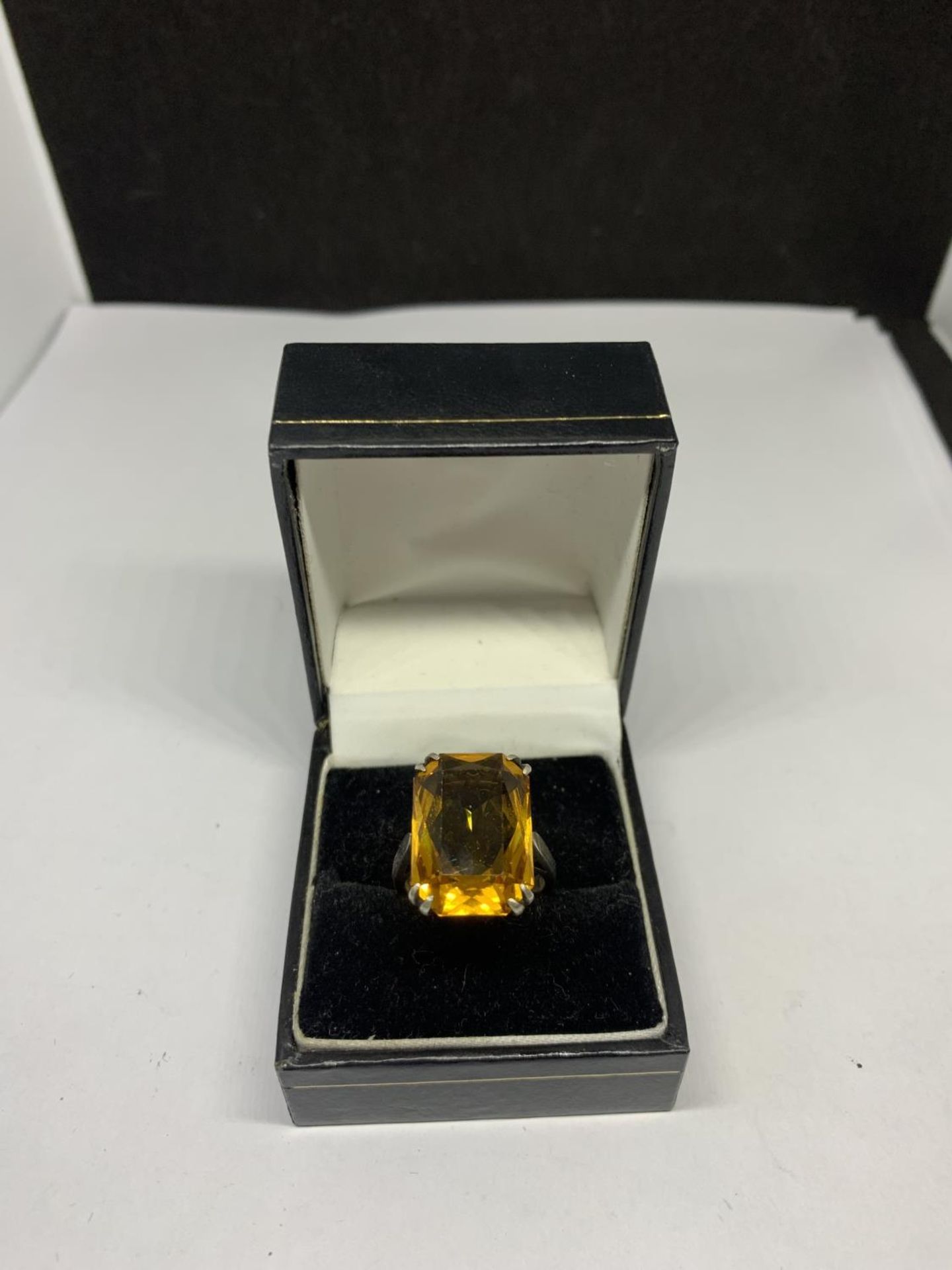 A SILVER AND YELLOW STONE RING IN A PRESENTATION BOX