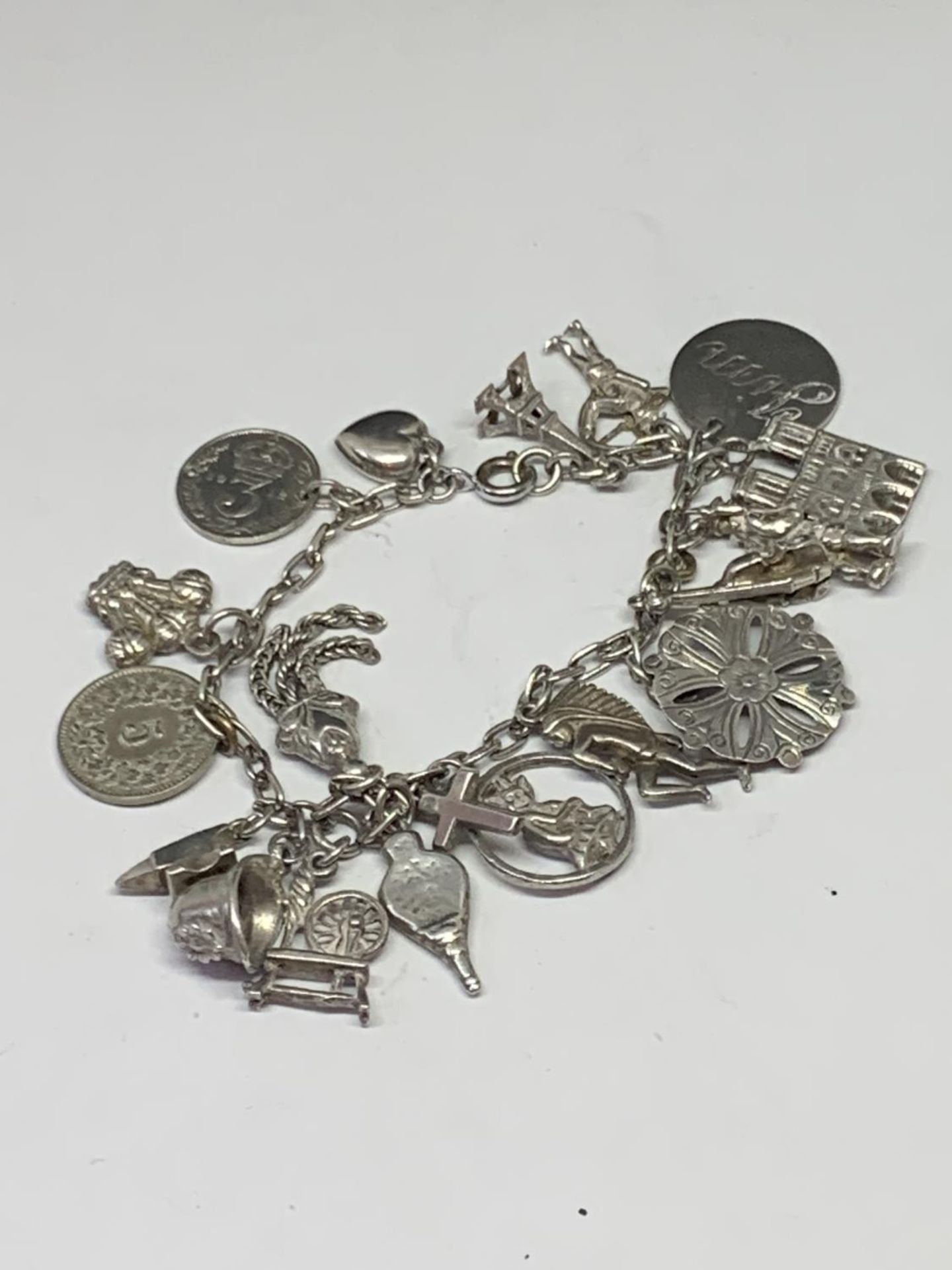 A SILVER CHARM BRACELET WITH NINETEEN CHARMS