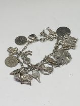 A SILVER CHARM BRACELET WITH NINETEEN CHARMS