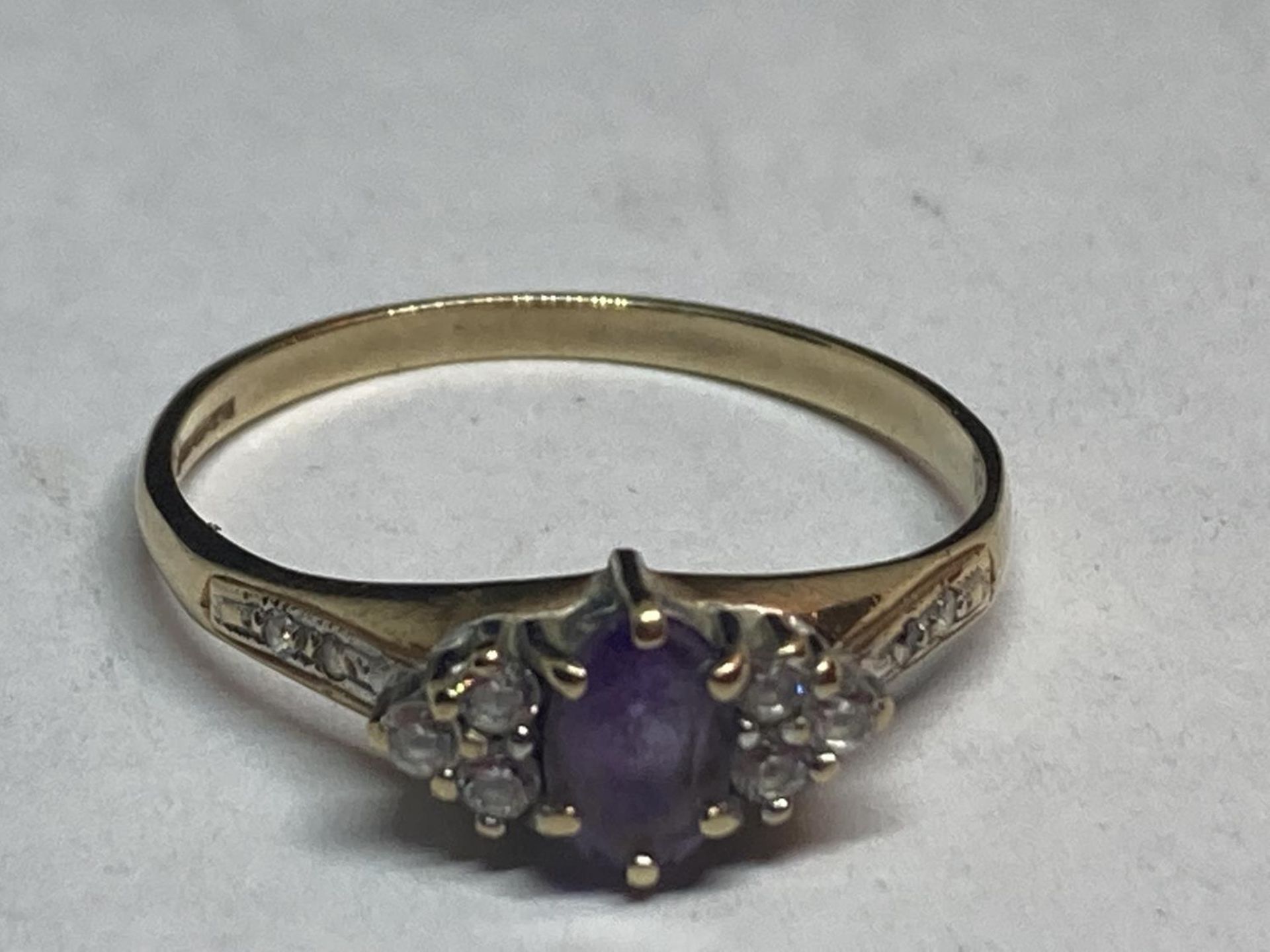 A 9 CARAT GOLD RING WITH A CENTRE AMETHYST SURROUNDED BY CUBIC ZIRCONIAS SIZE Q/R