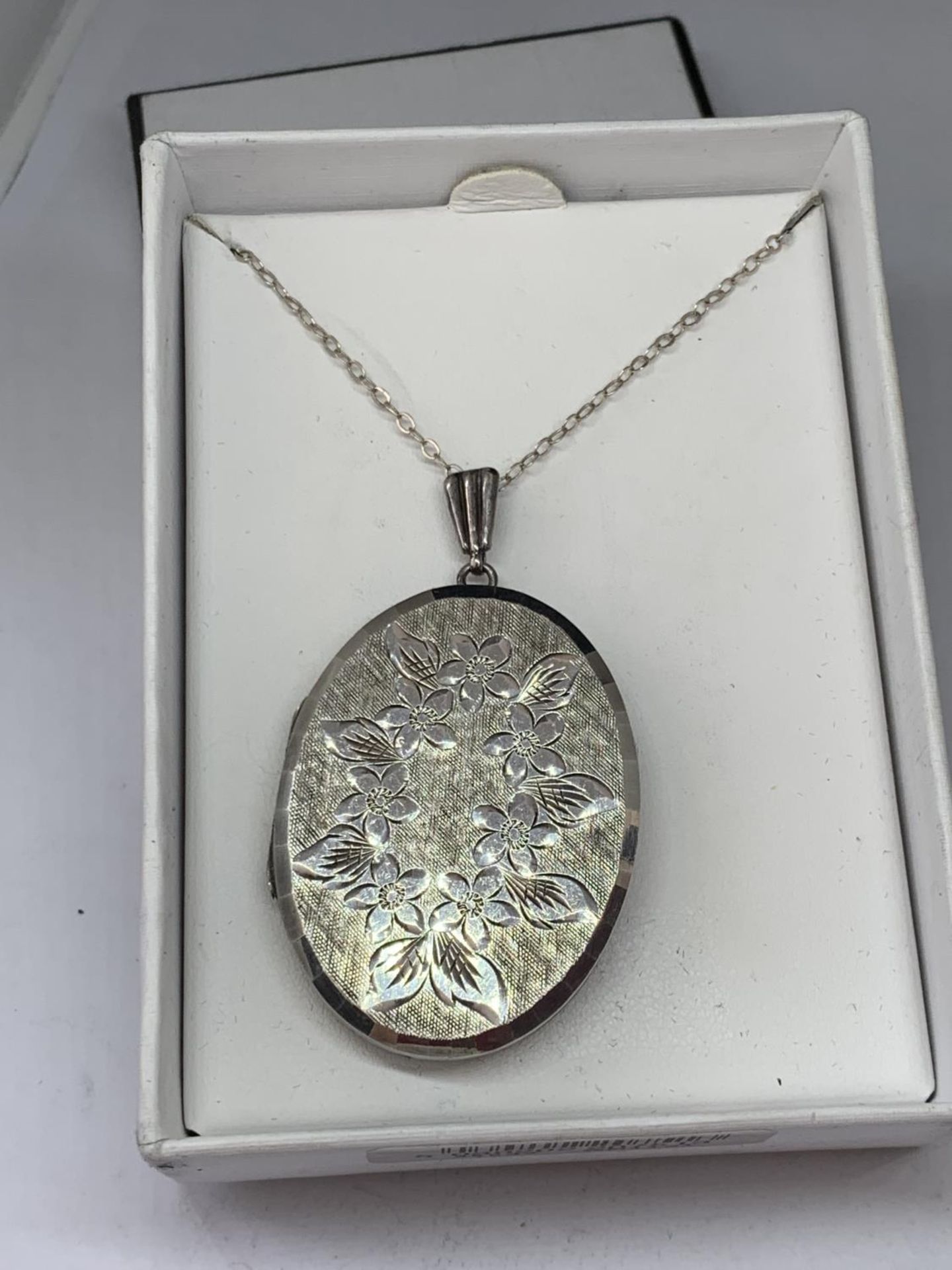 A SILVER OVAL LOCKET IN A PRESENTATION BOX