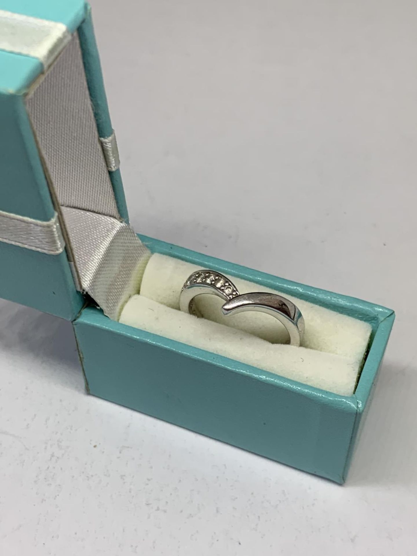 A SILVER RING IN A PRESENTATION BOX