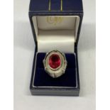 AN OVAL DESIGNER RING WITH RED STONE IN A PRESENTATION BOX