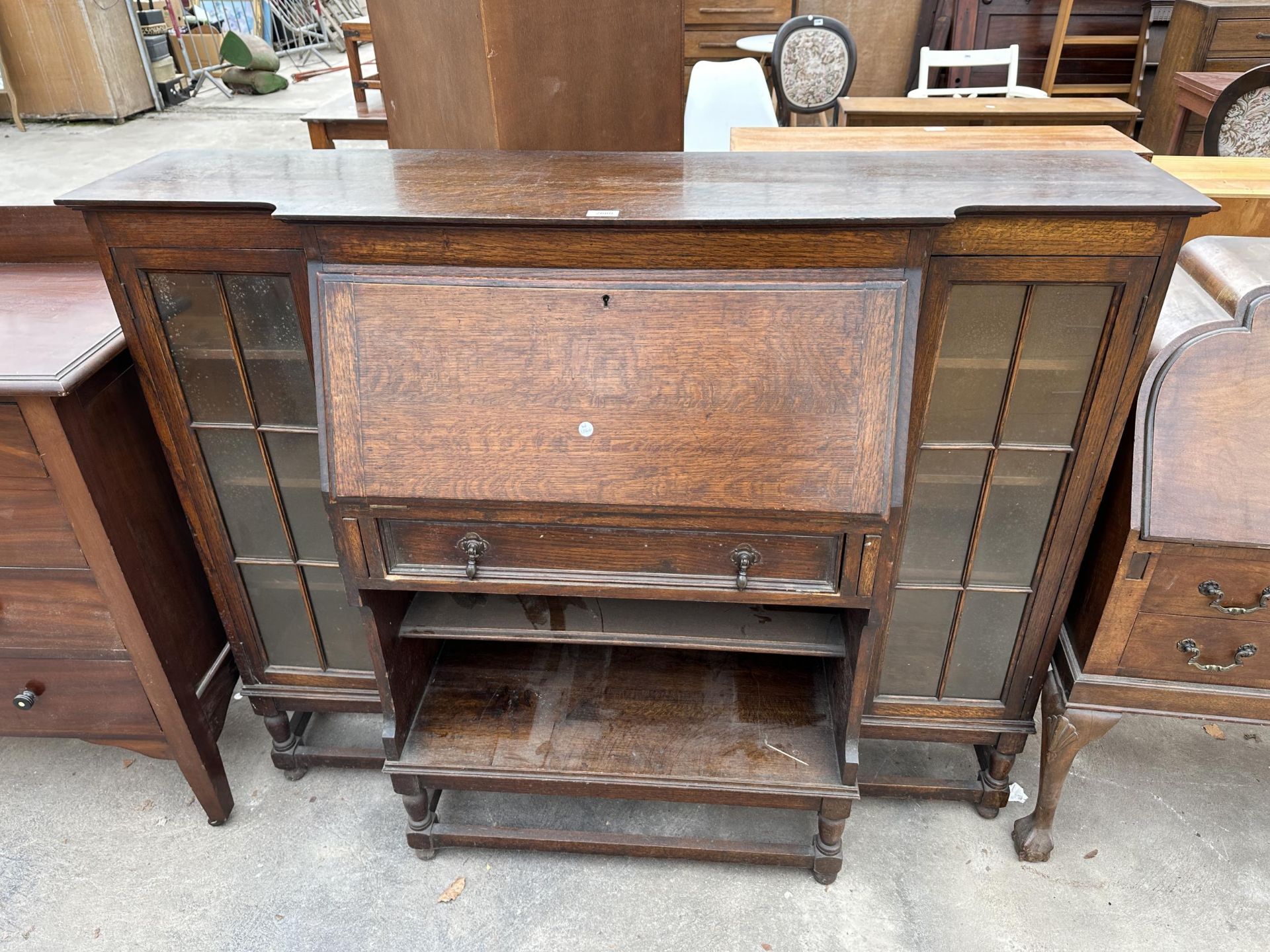 AN EARLY TWENTIETH CENTURY OAK BREAKFRONT SIDE BY SIDE BUREAU ON TURNED LEGS, 58" WIDE