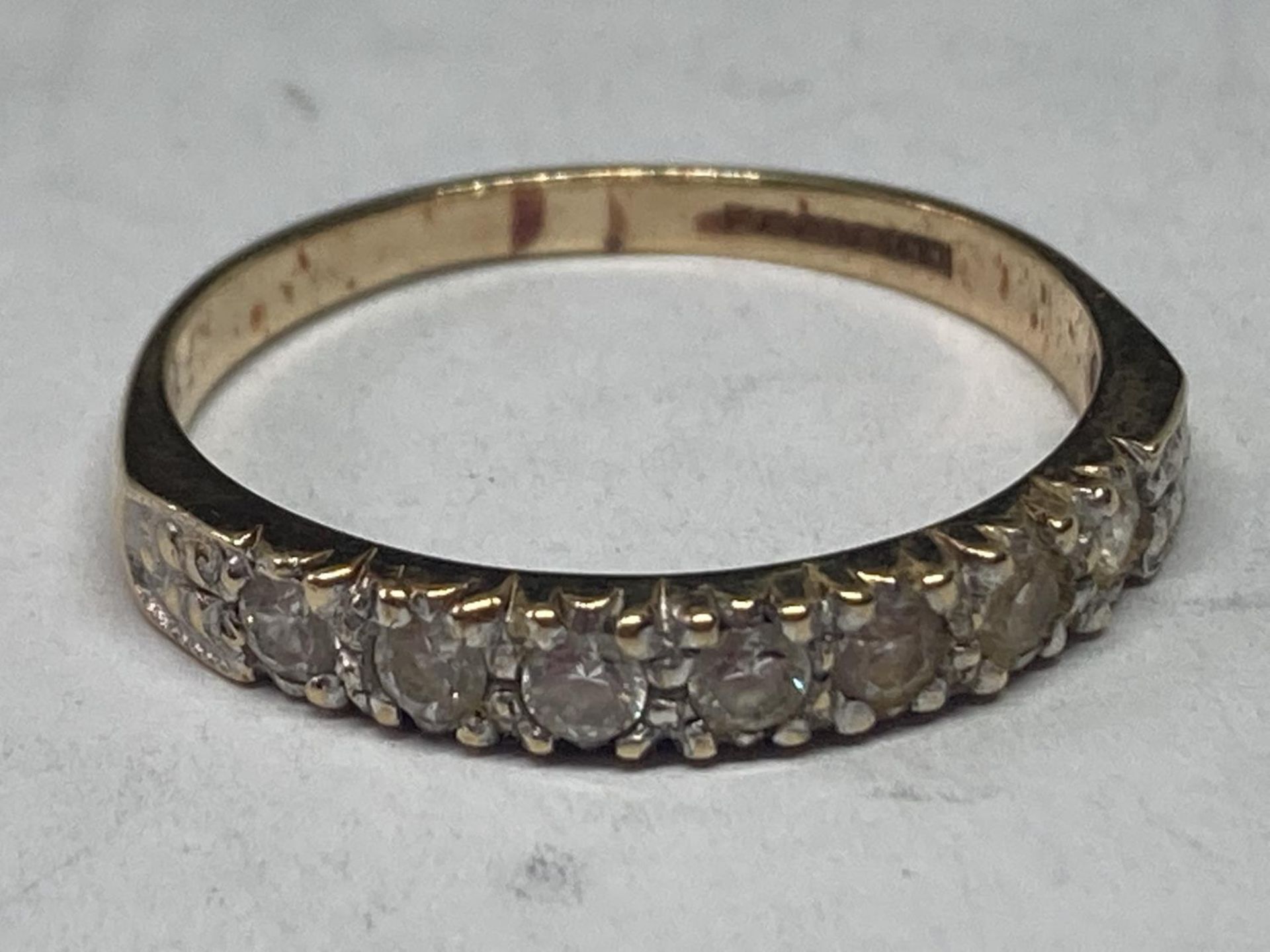 A 9 CARAT GOLD RING WITH IN LINE CUBIC ZIRCONIAS SIZE O/P