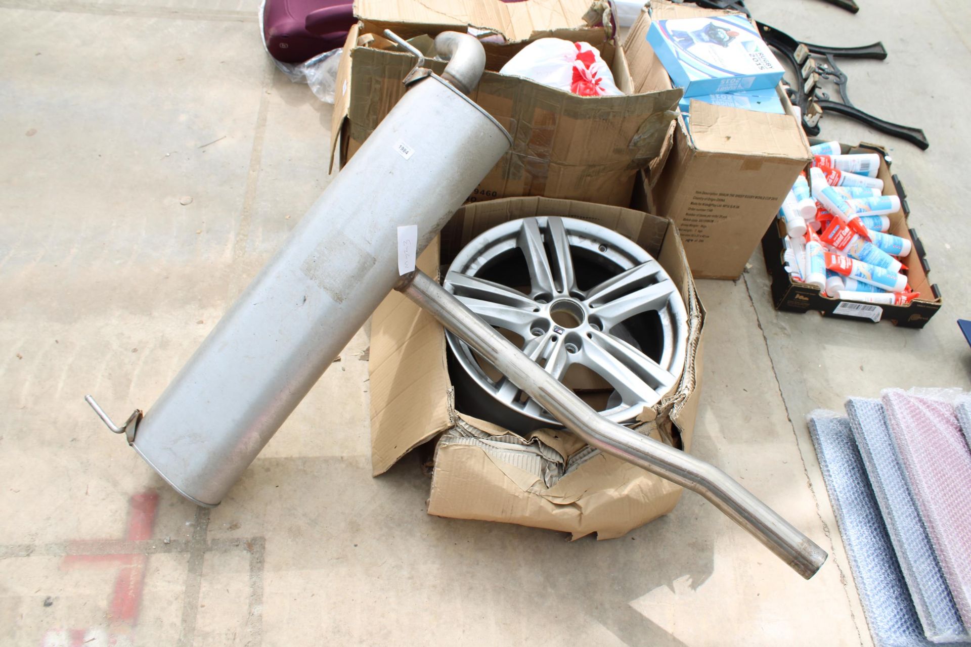 A BMW ALLOY CAR WHEEL AND AN EXHAUST PIPE KIT