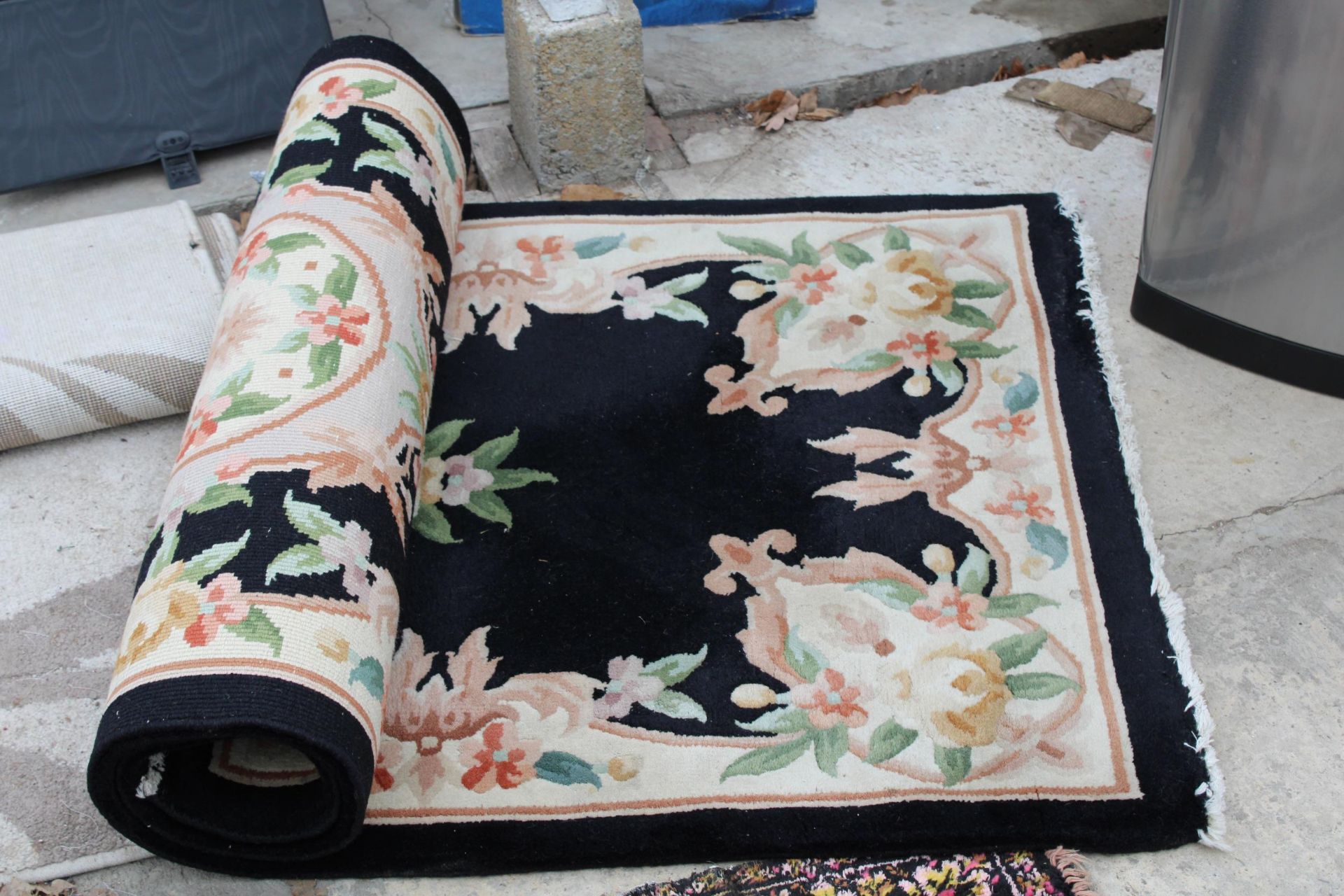 A BLACK PATTERNED FRINGED RUG