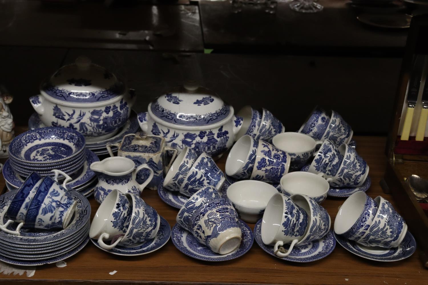 A BLUE AND WHITE WILLOW PATTERN PART DINNER SERVICE TO INCLUDE SERVING TUREENS, BOWLS, SUGAR BOWL,
