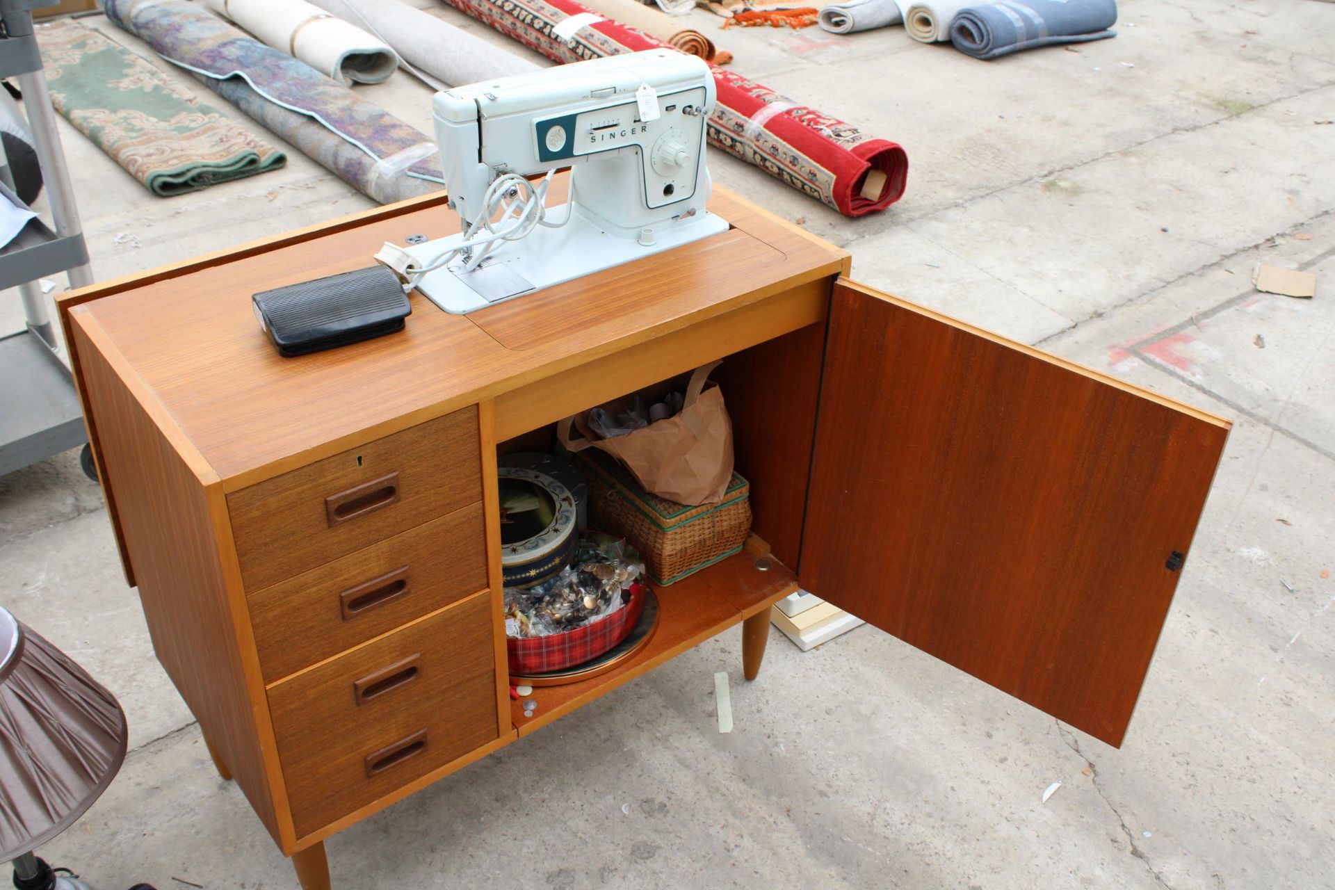 A RETRO TEAK SEWING CABINET WITH ELECTRIC SINGER SEWING MACHINE AND ACCESSORIES