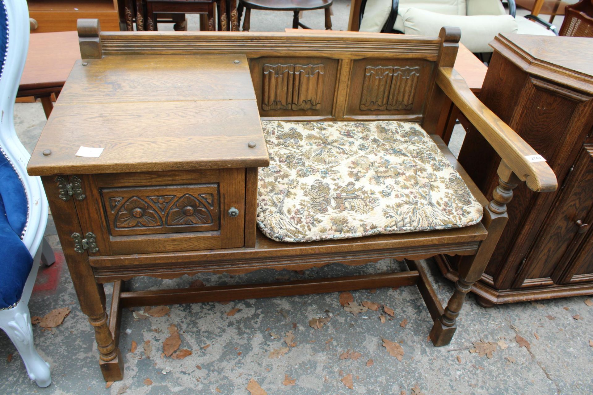 AN OAK OLD CHARM STYLE TELEPHONE TABLE/SEAT WITH LINEN FOLD BACK ON TURNED LEGS