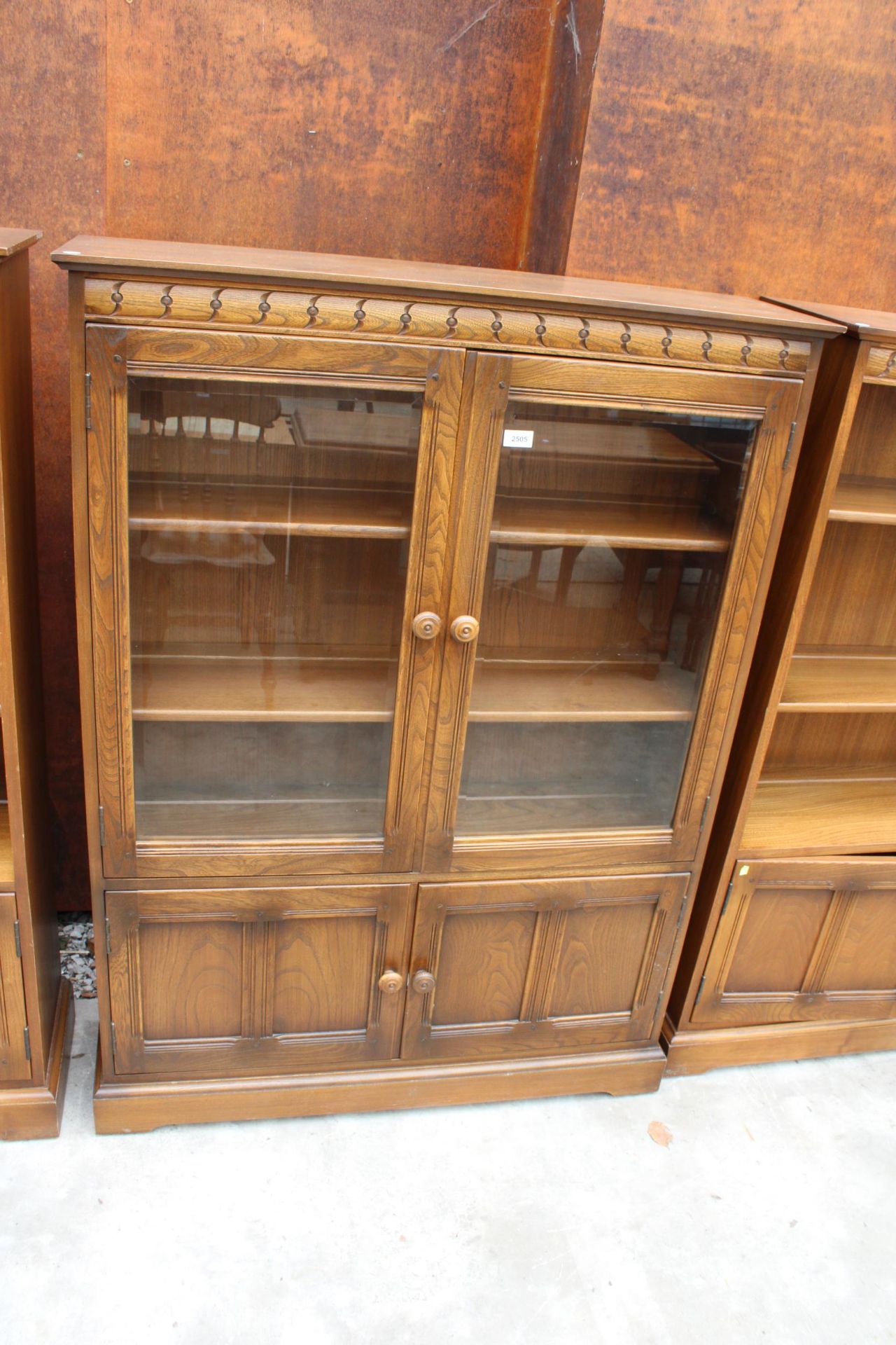 AN ERCOL BLONDE TWO DOOR BOOKCASE WITH CUPBOARD TO BASE 39.5" WIDE
