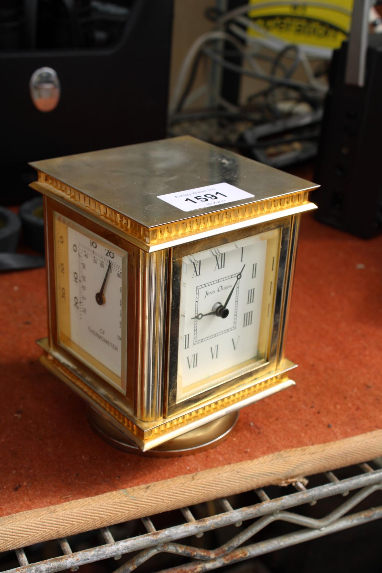 A BRASS JENS OLSEN REVOLVING DESK CLOCK WITH FOUR FACES, TWO BEING CLOCKS, ONE THERMOMETER AND ONE