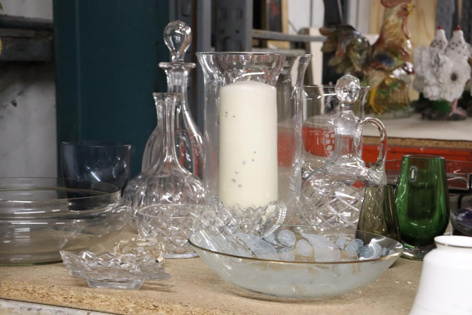 A QUANTITY OF GLASSWARE TO INCLUDE DECANTERS, BOWLS, VASES, CANDLE HURRICANE, ETC.,